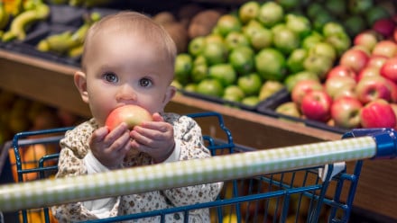baby eating apple in grocery cart