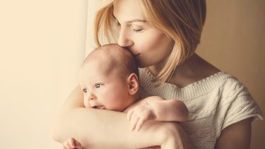 blonde woman kissing her baby