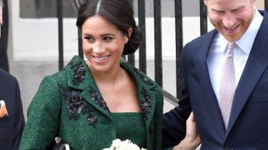 meghan markle smiling with prince harry in a green coat