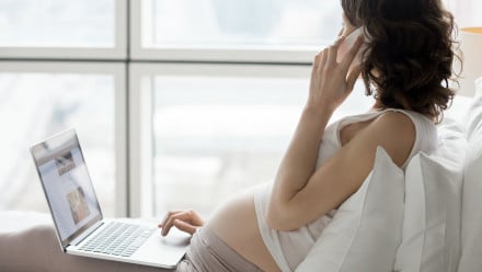 Pregnant woman on her phone and laptop