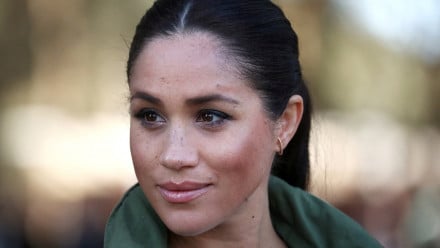meghan markle with her hair in a ponytail and a green jacket