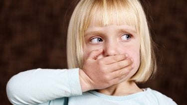 blond little girl covering her mouth
