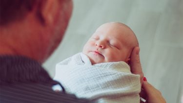 father looks at swaddled baby