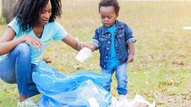 Mother with kid recycling and picking up trash in the grass