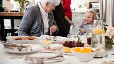 Grandma and young girl smile at each other during brunch