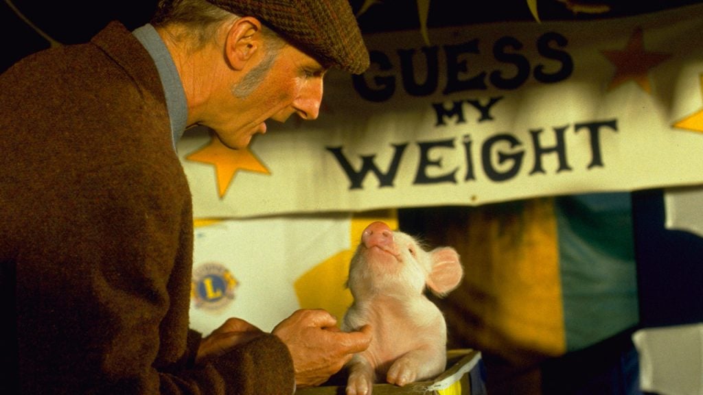 Promo image for Babe showing a farmer petting a piglet