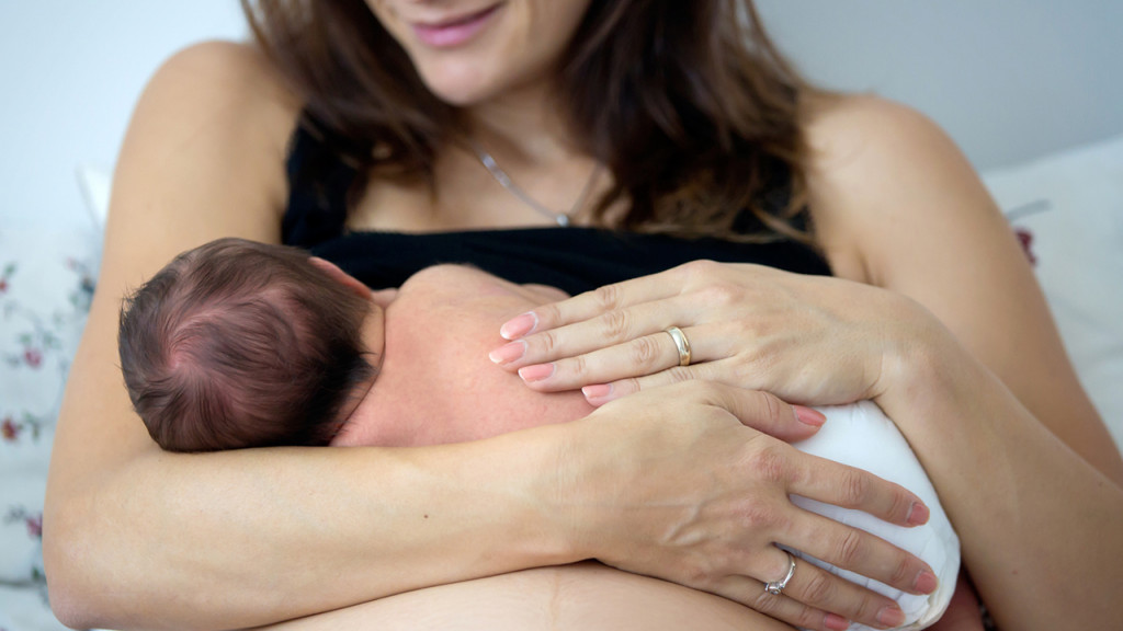 New mother breastfeeds her newborn baby in underwear