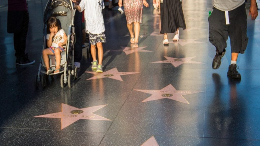 People with a stroller walking on the Hollywood Walk of Fame