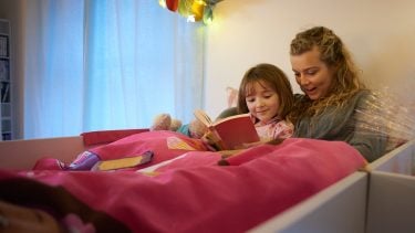 Babysitter reads to young girl at bedtime