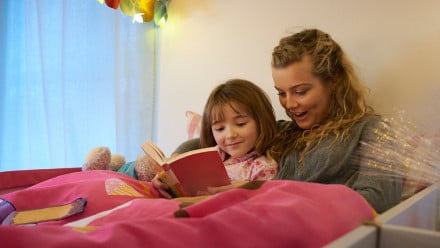 Babysitter reads to young girl at bedtime