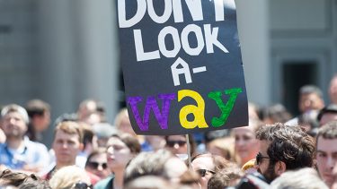 group of protesters with "Don't Look Away" sign