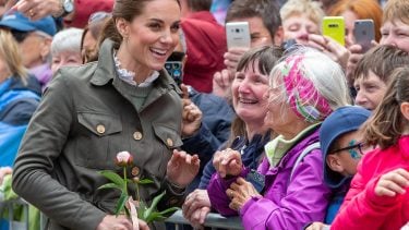 A smiling Duchess Kate chats with two women.