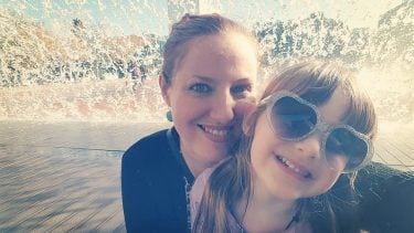 Mother and daughter smile in front of fountain