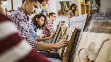 Teen boy concentrates on drawing during art class