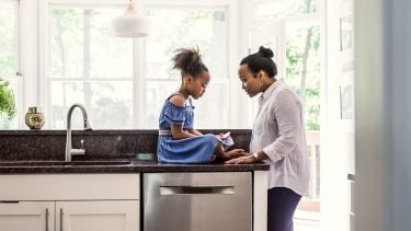A mother talks to her young daughter in the kitchen
