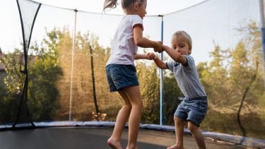 Two kids jumping on a trampoline together