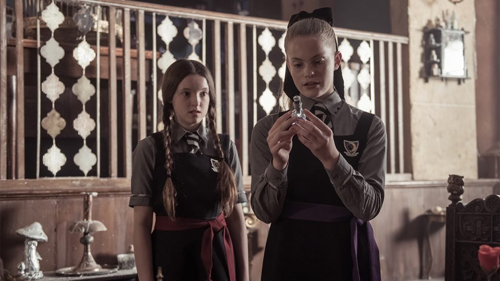 Promo image for the Worst Witch showing two students looking at a glass vial