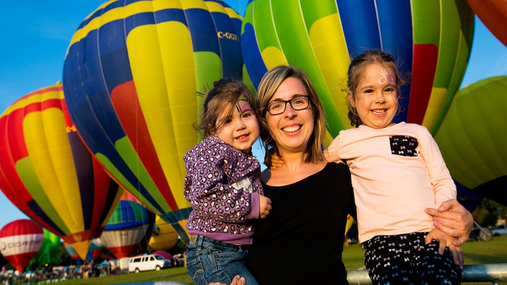 Family smiles in front of hot air balloons
