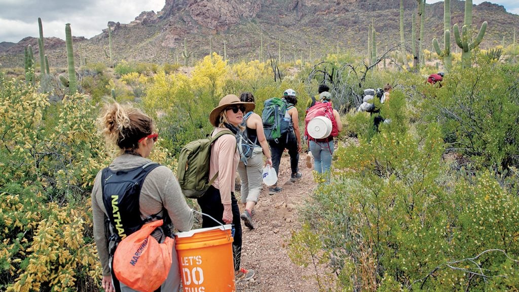 Volunteers for No More Deaths walk with buckets of food and jugs of water for undocumented immigrants near Ajo, Arizona 