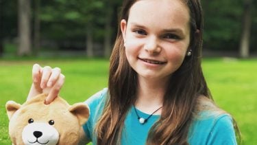 a 12-year-old girl holding up a teddy bear