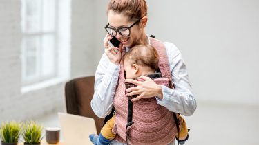 Mom on the phone while holding baby in carrier