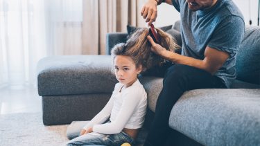 Young girl getting her hair brushed by her dad