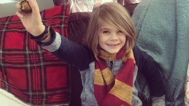 Little boy wearing Griffindor scarf and holding a snitch