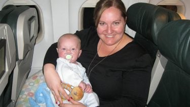 The author, Jen McLellan, holds her son while sitting in a seat on a plane