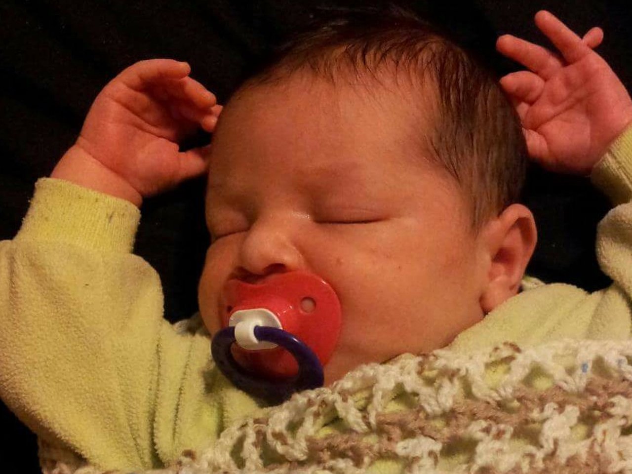 close up of new born with soother in his mouth and six fingers on one hand