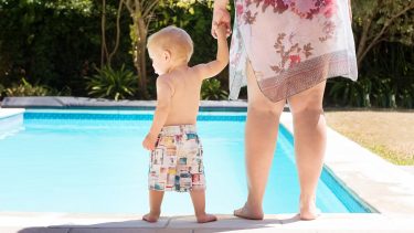 a boy and his mom standing by edge of pool