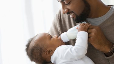 Milk allergy: Father feeding baby a bottle of milk