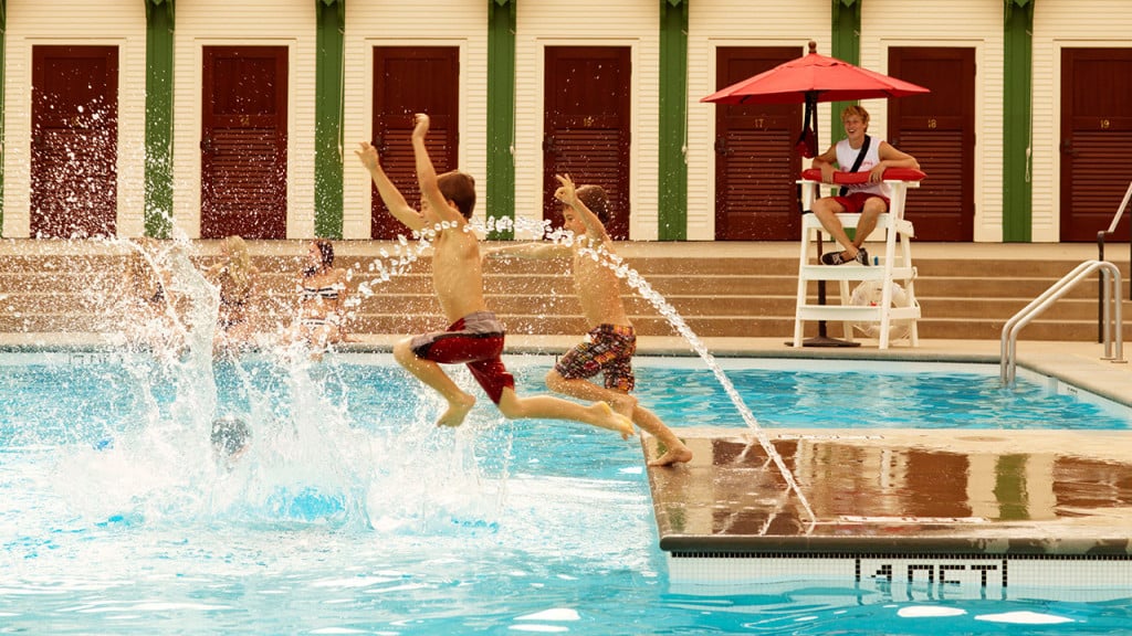 Two kids jumping into a pool