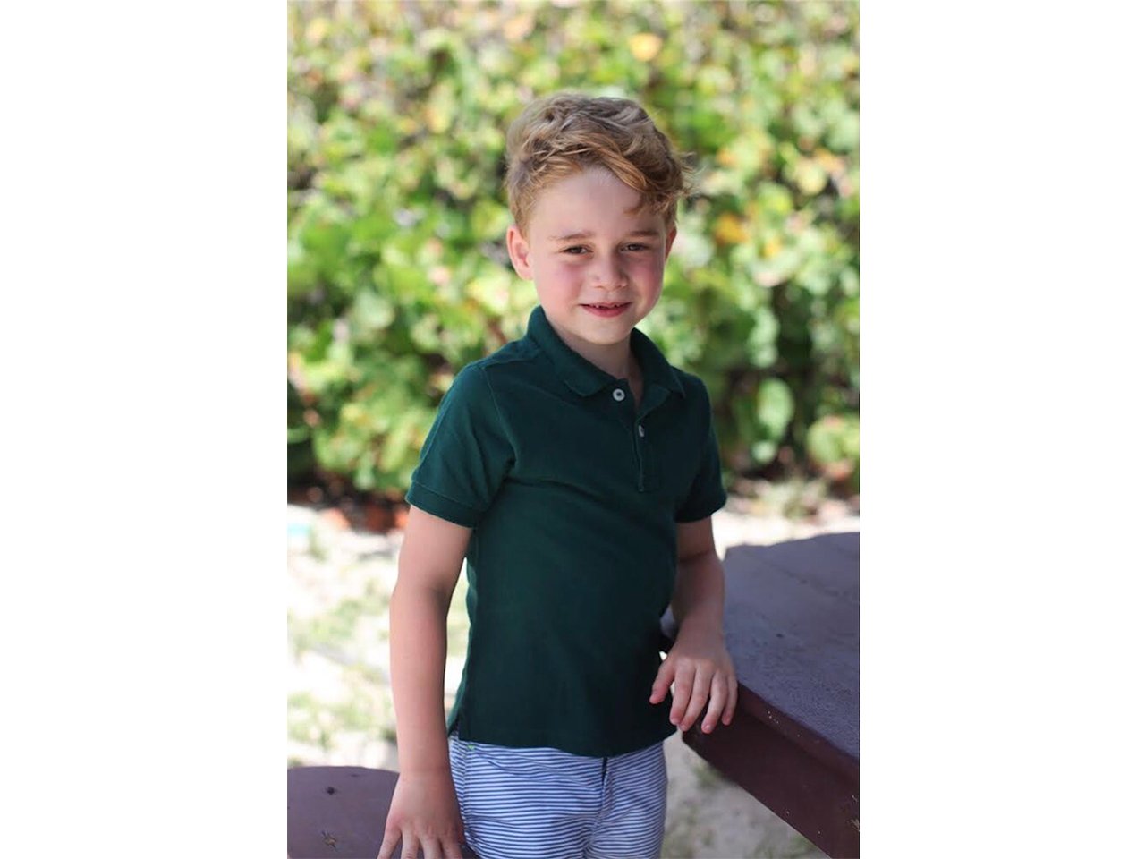 Prince George posing in a green polo shirt
