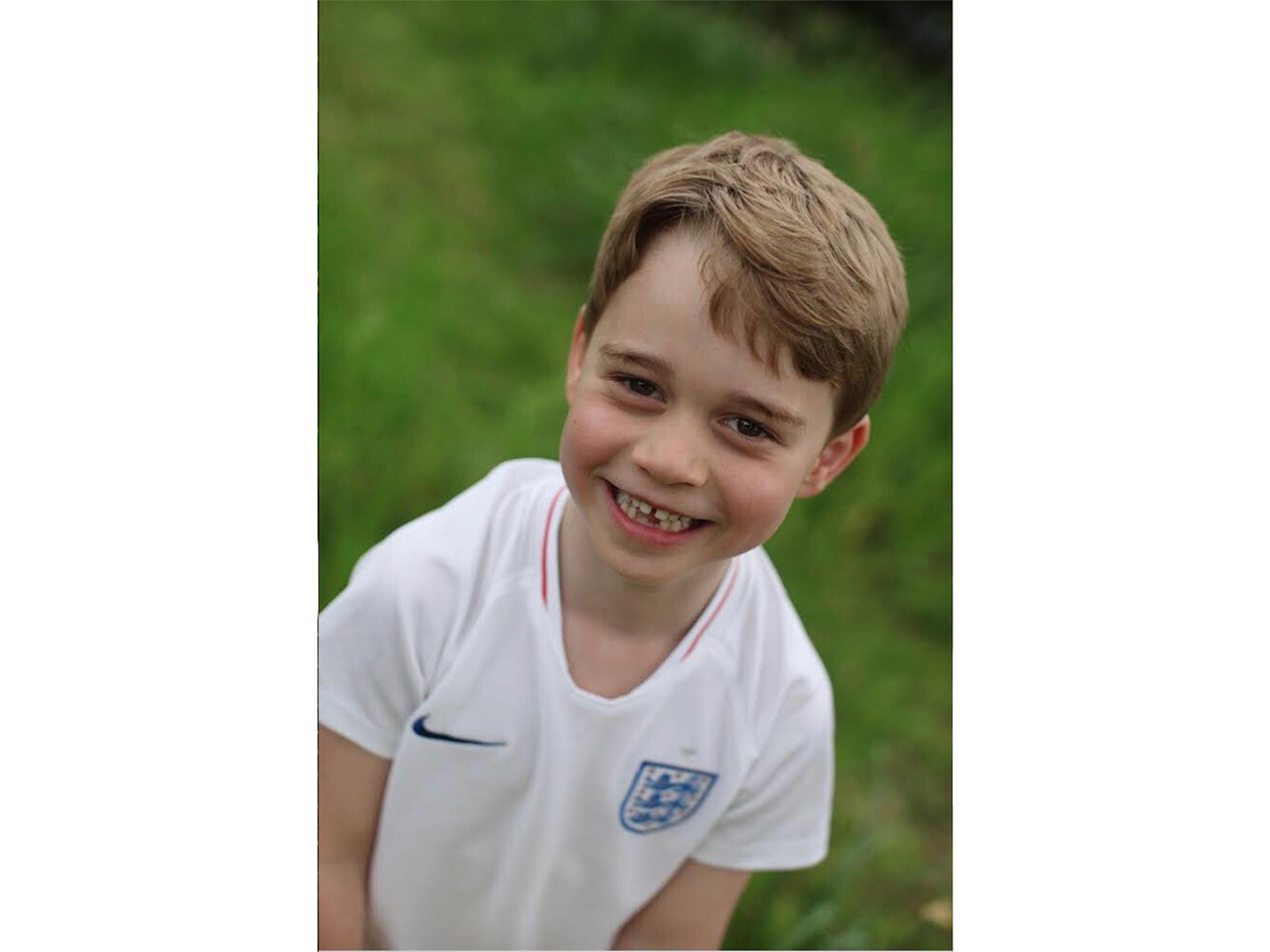 Prince George smiling in a soccer shirt