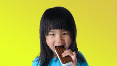 Child bites into an ice cream sandwich