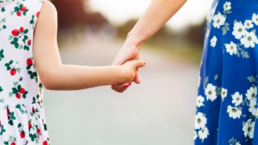 Mom and daughter in summer dresses holding hands