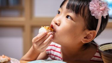 Little girl eating a rice ball