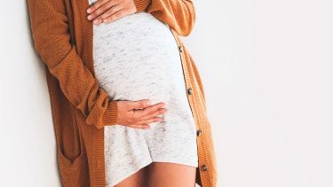 Online maternity stores Canada: Pregnant woman leaning against a wall