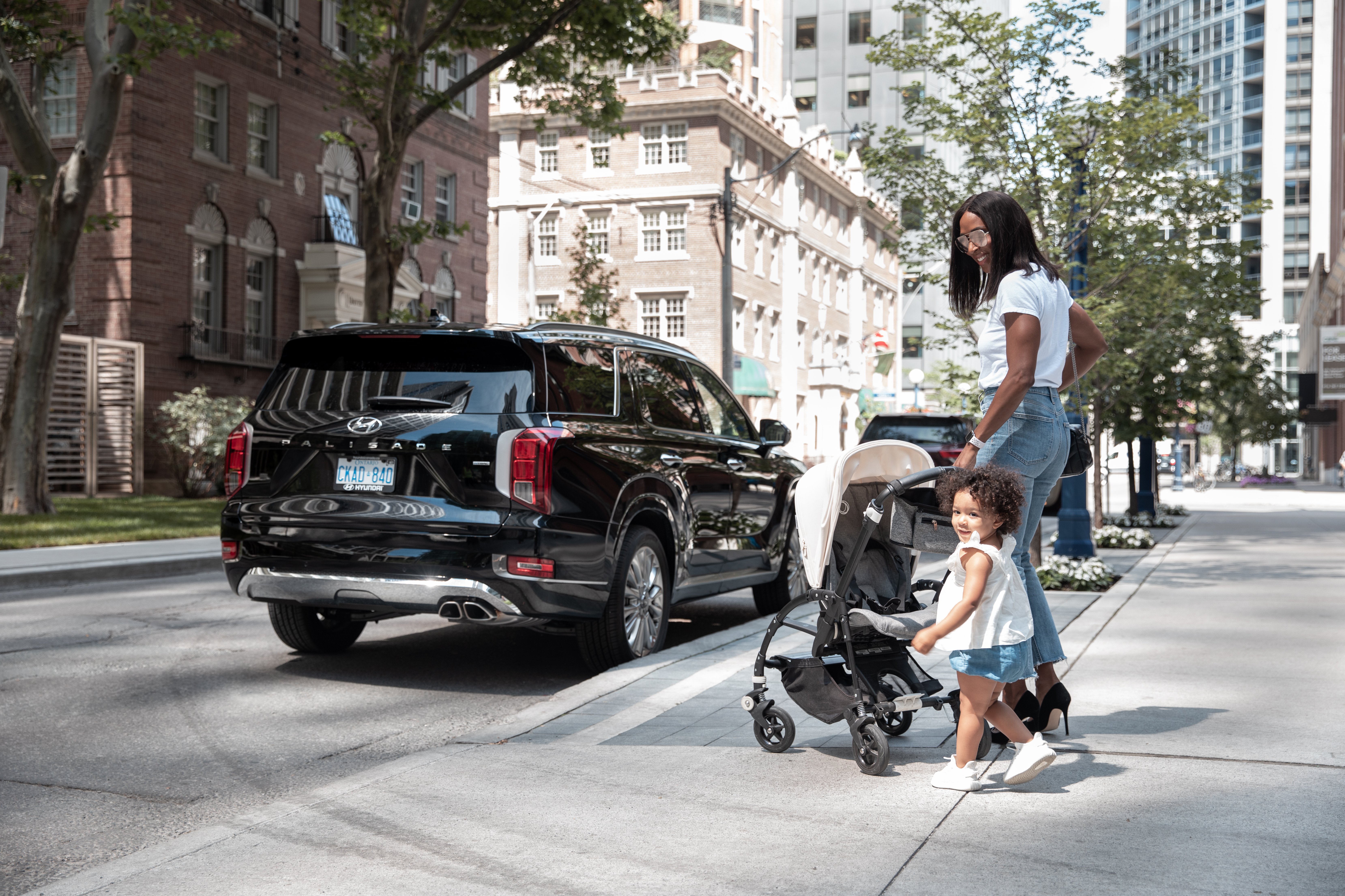 Woman and toddler with stroller walking up to the Hyundai Palisade