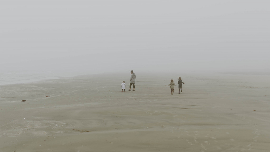 Three kids and mom play on beach