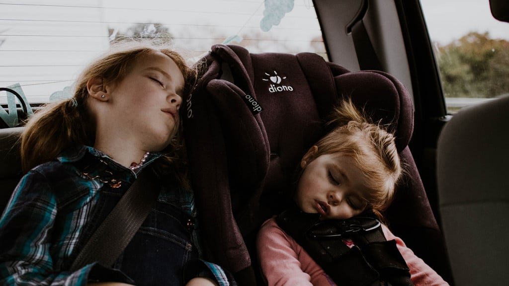 Two girls sleeping in the car