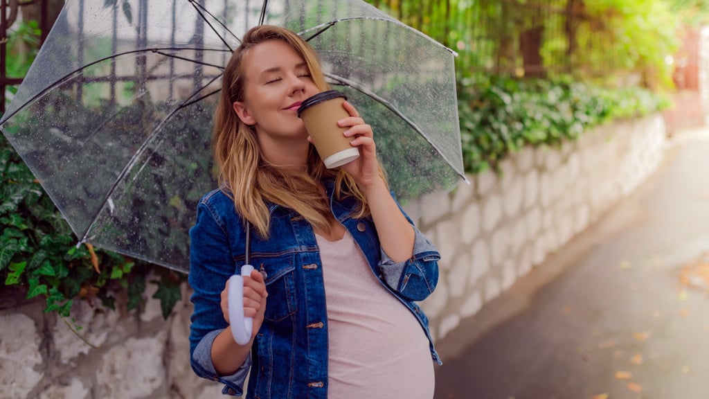 Pregnant woman sipping coffee in the rain