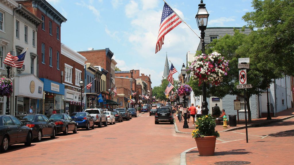 Houses, cars, an American flag and flowers on main street in Annapolis