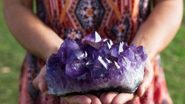 Birthstones by month: Girl holding an amethyst rock