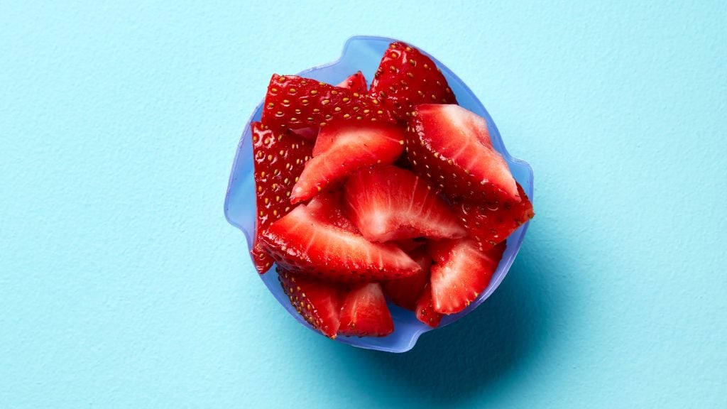 sliced strawberries in a blue cup