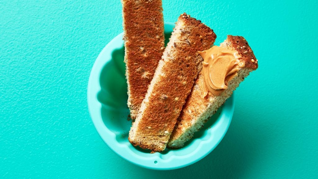 Toast strips with nut butter in a teal cup