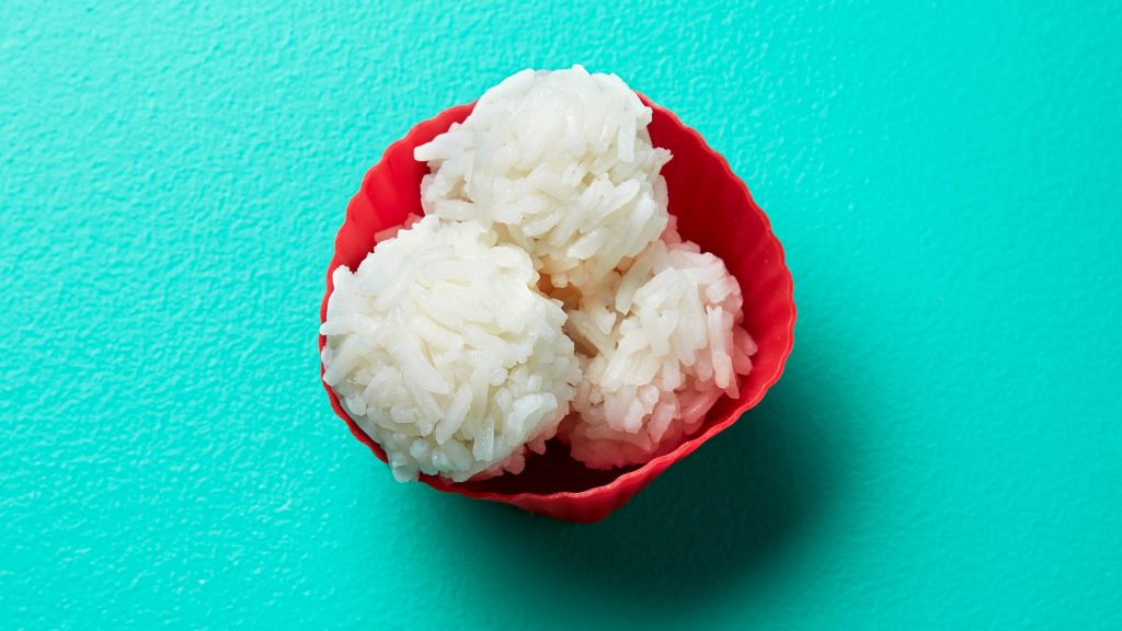 three rice balls in a red silicone cup
