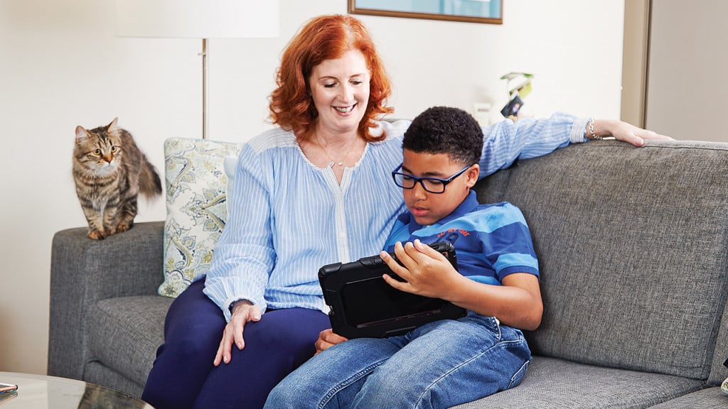 A 50-year-old woman looking at an ipad with her 10-year-old son