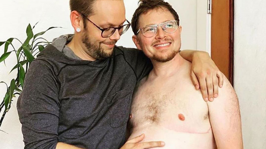 queer couple shows of pregnant dad's baby bump