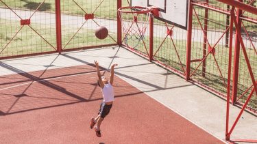A child attempts to shoot some hoops.